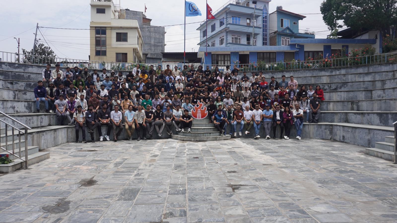 The BarCamp Kathmandu 2025 group photo: around a hundred and fifty attendees filling the tiers of an outdoor amphitheatre.