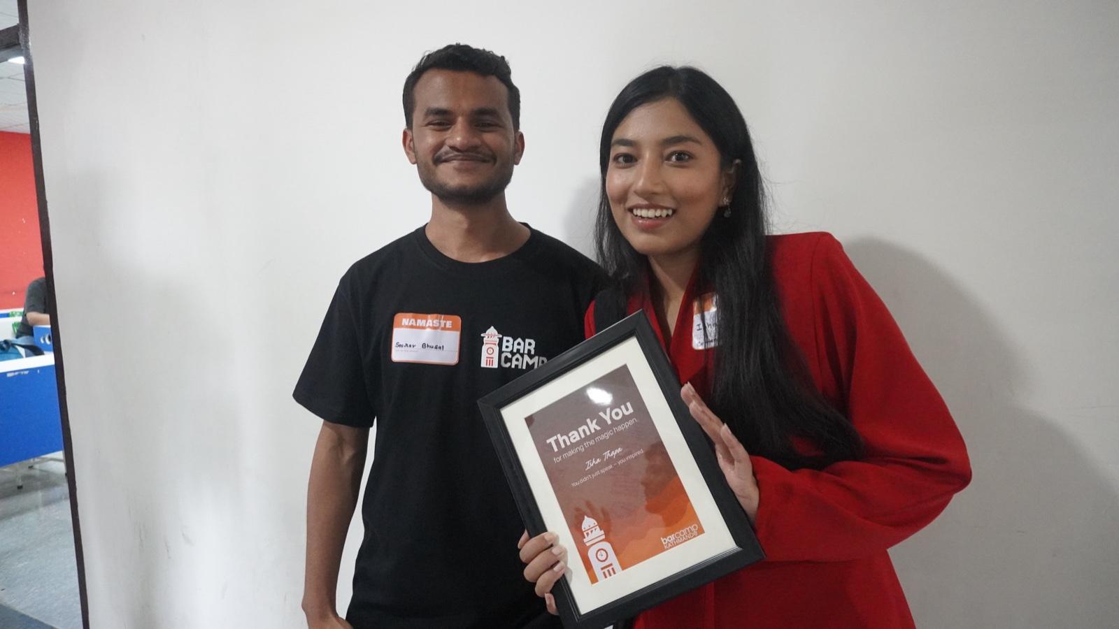 Two organisers holding up a framed BarCamp thank-you certificate for the camera.